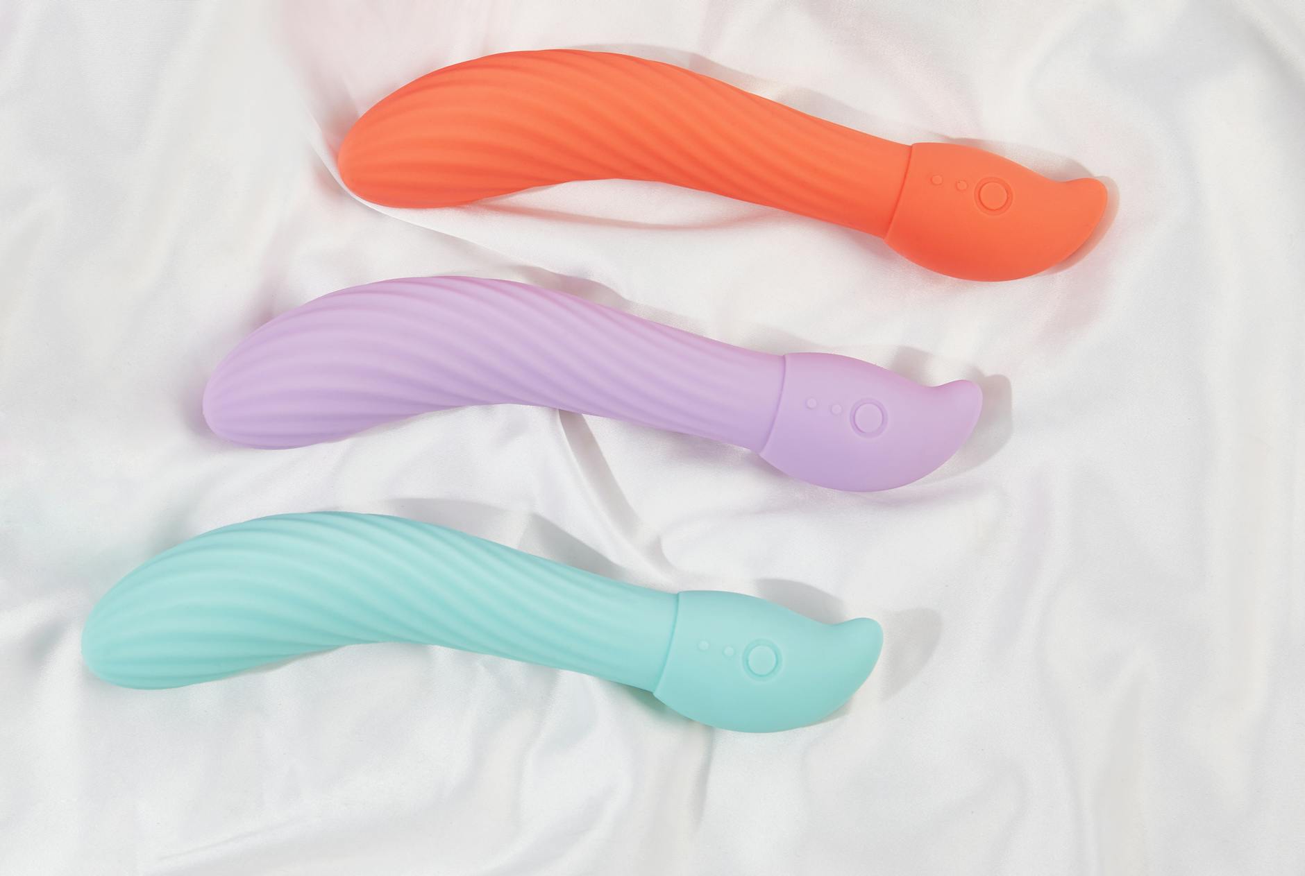 Gros plan d'une main tenant un vibromasseur moderne contre un fond minimaliste