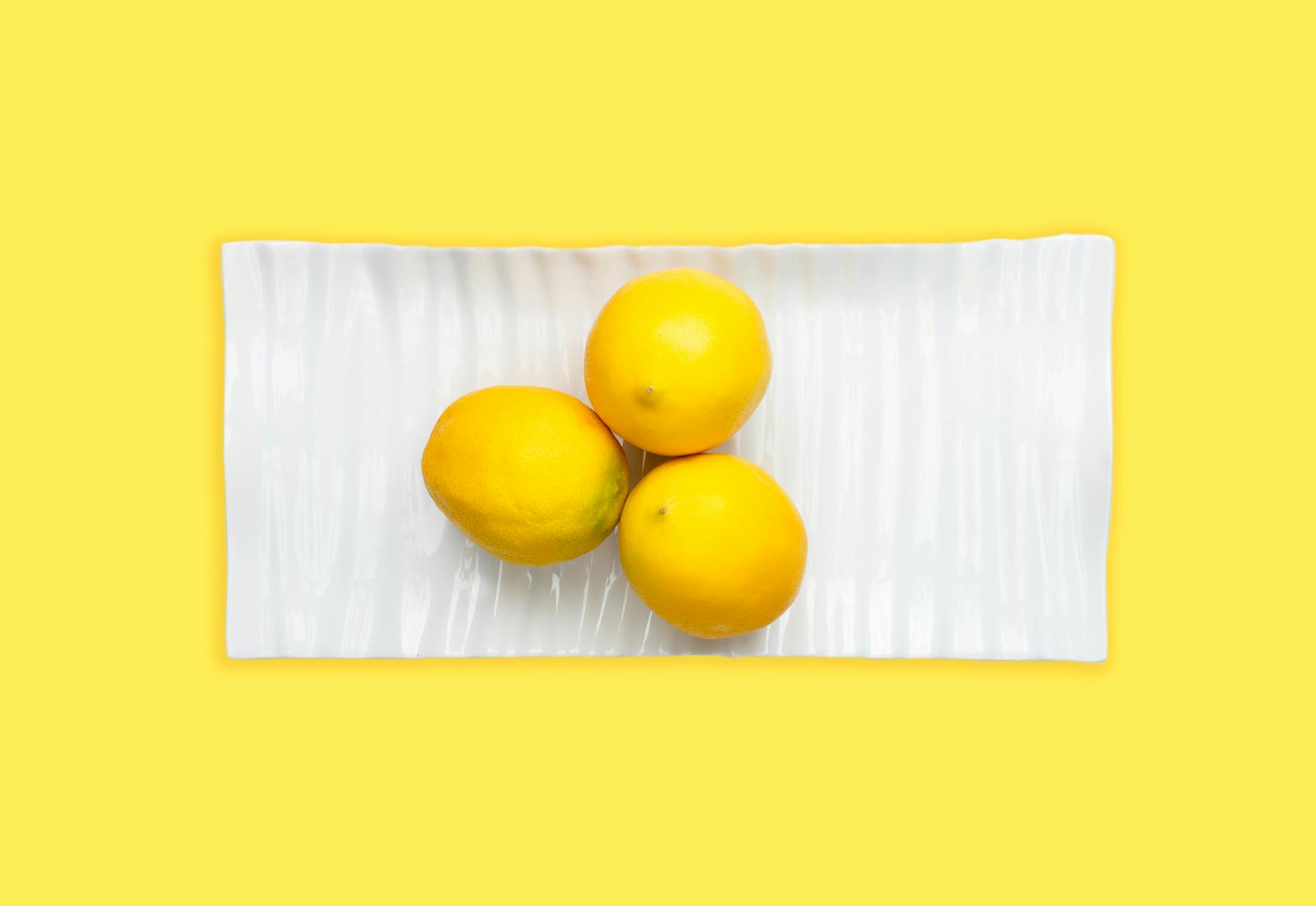 Fresh lemons on a white plate with yellow background, symbolizing bright solutions to timing challenges