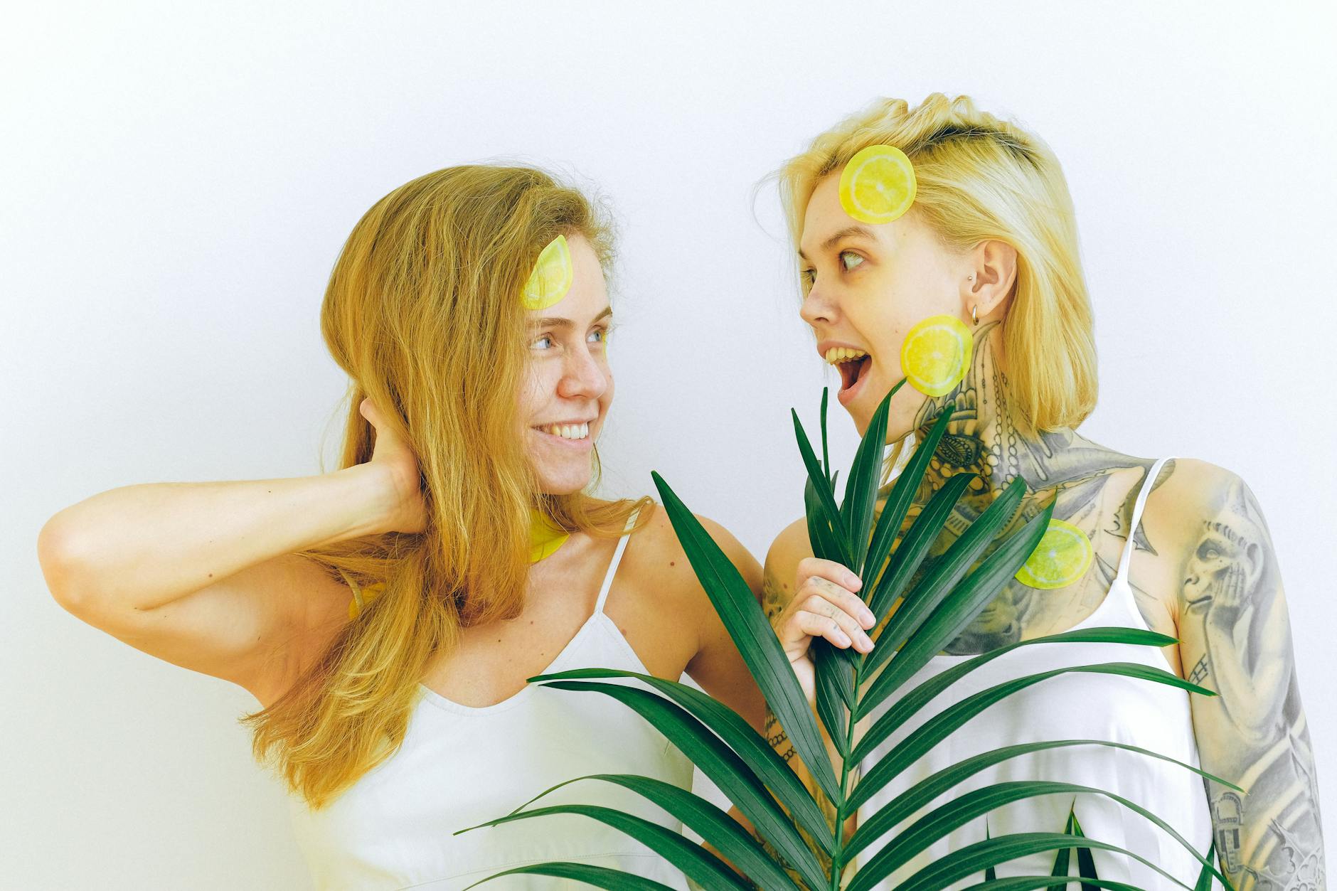 Deux femmes souriantes partageant un moment joyeux avec des tranches de citron et une plante tropicale, exprimant la confiance et le plaisir retrouvés