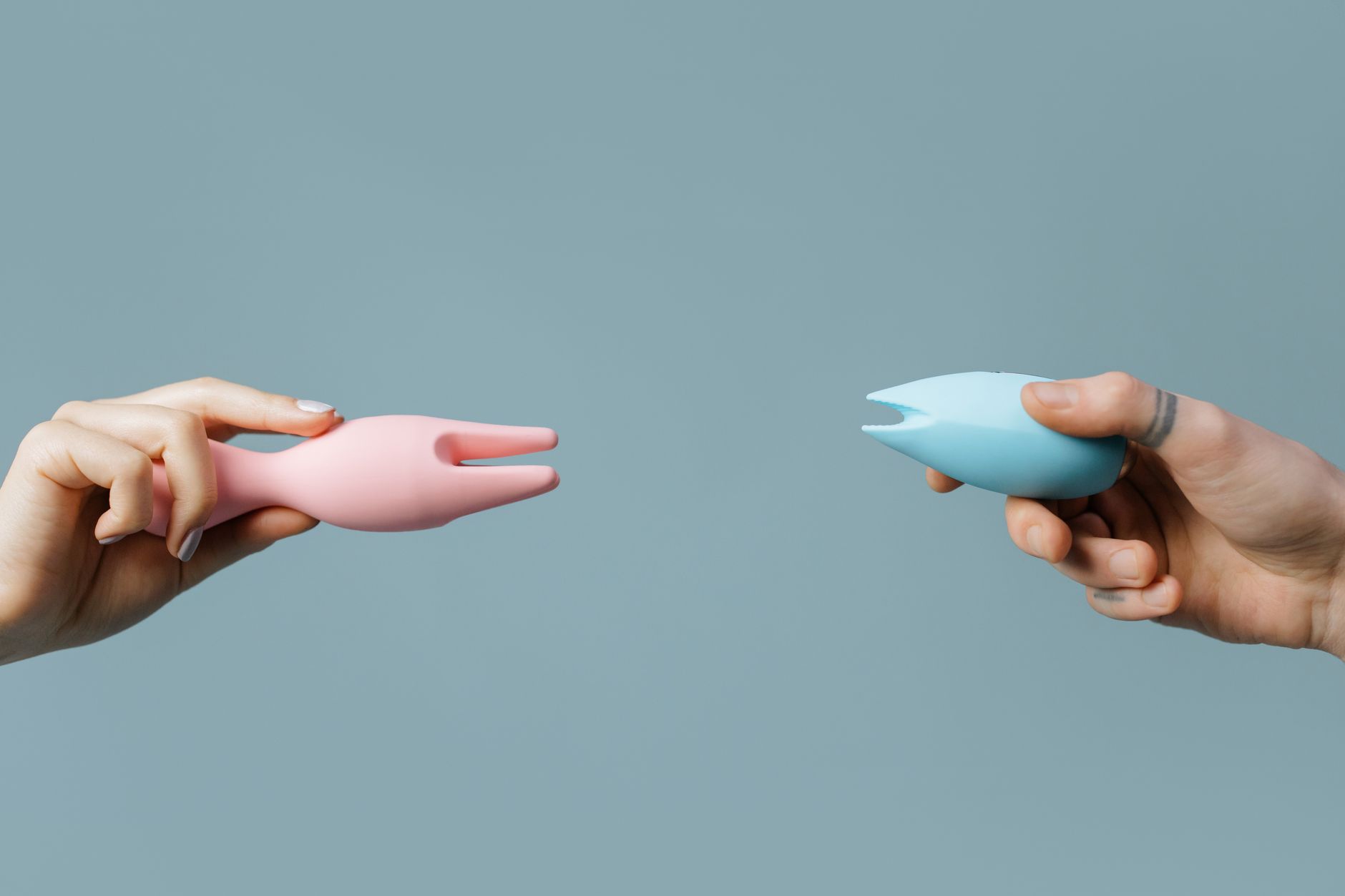 Gros plan des mains tenant un vibromasseur bleu élégant sur fond violet, symbole d'intimité partagée et reconnexion