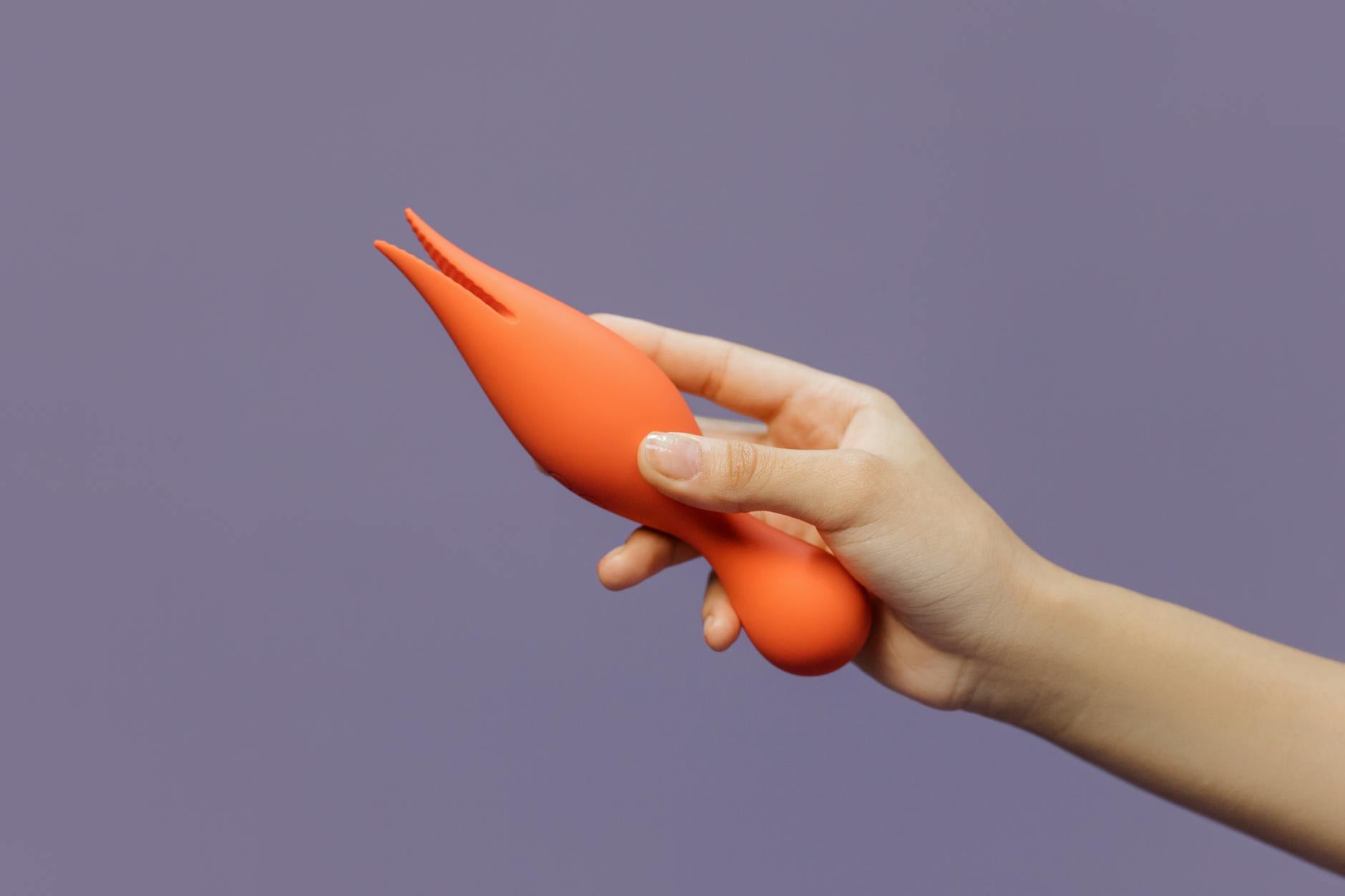 Hand holding a vibrator against a minimalistic backdrop, showcasing modern sensuality and pleasure exploration.