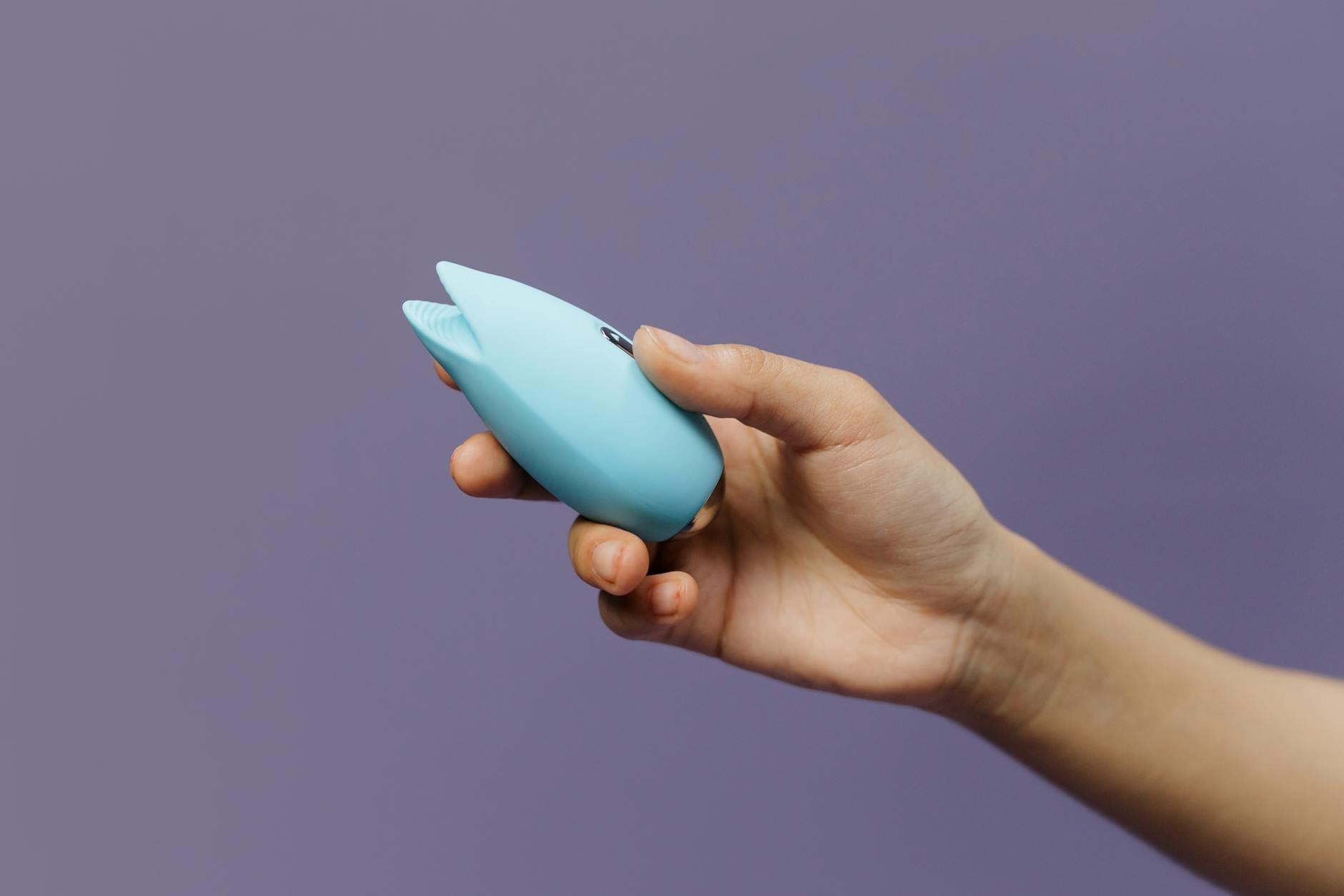 Un vibromasseur citron bleu tenu dans une main contre un fond violet, promouvant l'amour de soi et la sexualité