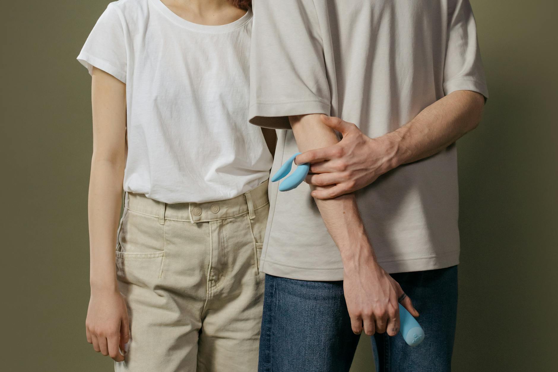 A hand holding an orange vibrator against a purple backdrop, symbolizing sensuality and self-care